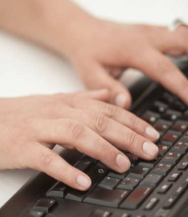 Hände, deren Finger über eine Computertastatur sind.